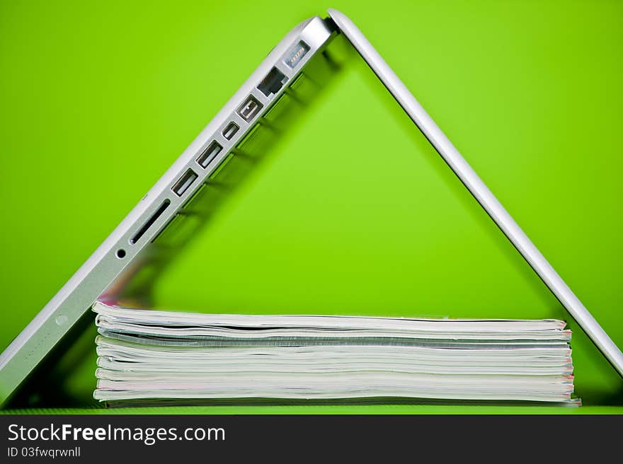 Stack of books and a laptop isolated over a green background. Stack of books and a laptop isolated over a green background