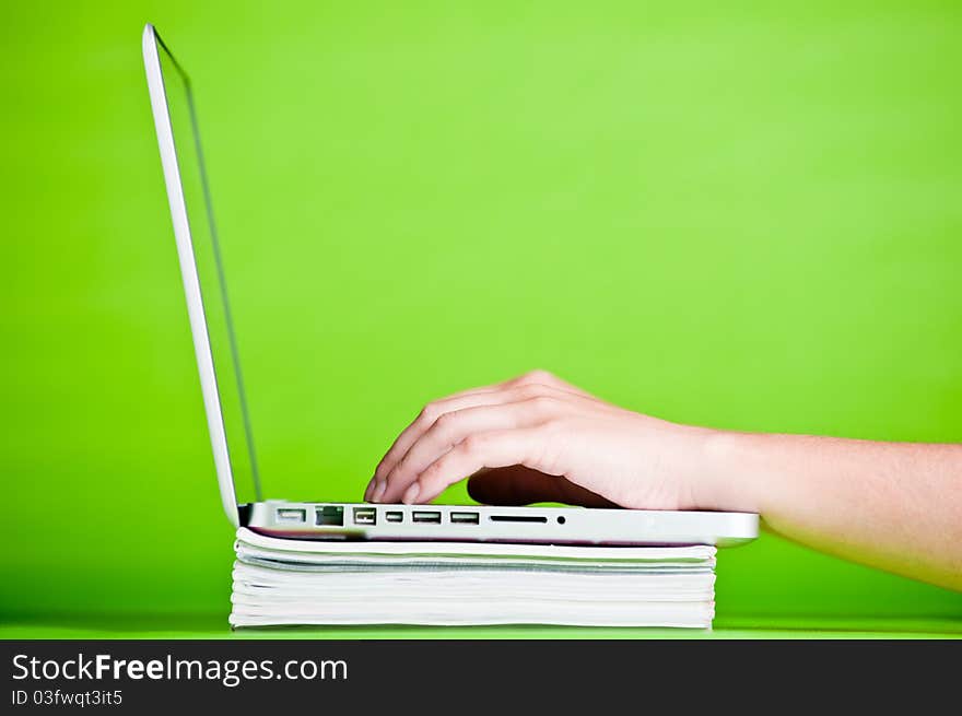 Stack of books and a laptop isolated over a green background. Stack of books and a laptop isolated over a green background