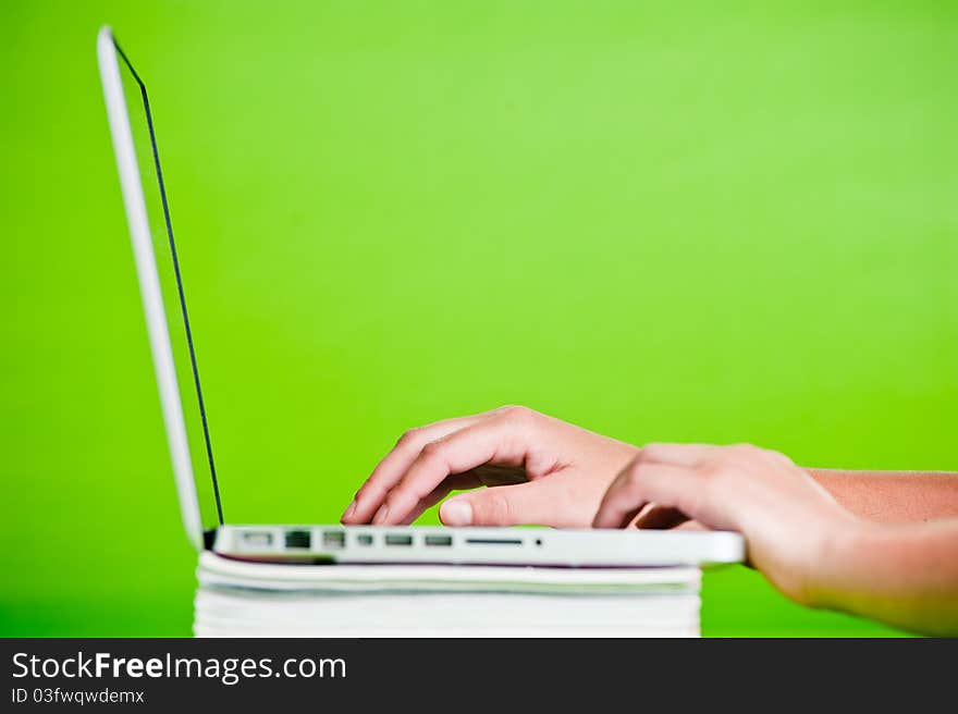 Woman using a laptop on stack of books isolated over a green background. Woman using a laptop on stack of books isolated over a green background