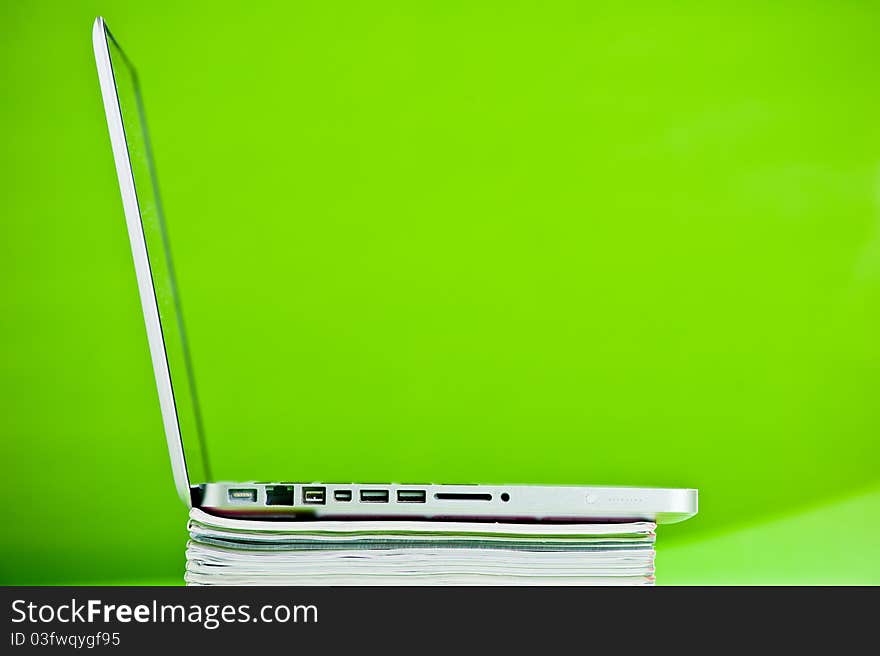 Stack of books and a laptop isolated over a green background. Stack of books and a laptop isolated over a green background