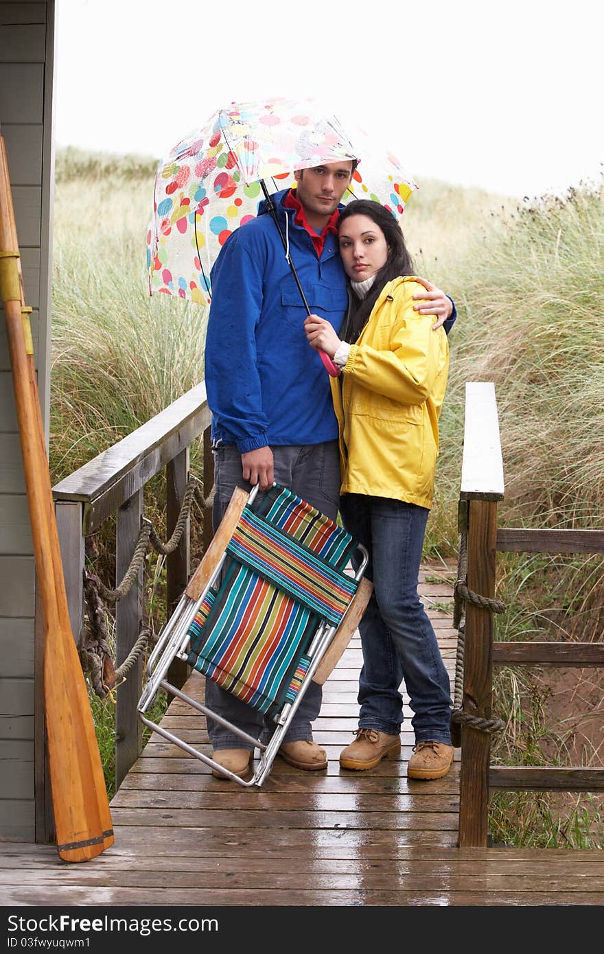 Young couple on beach with umbrella unhappy