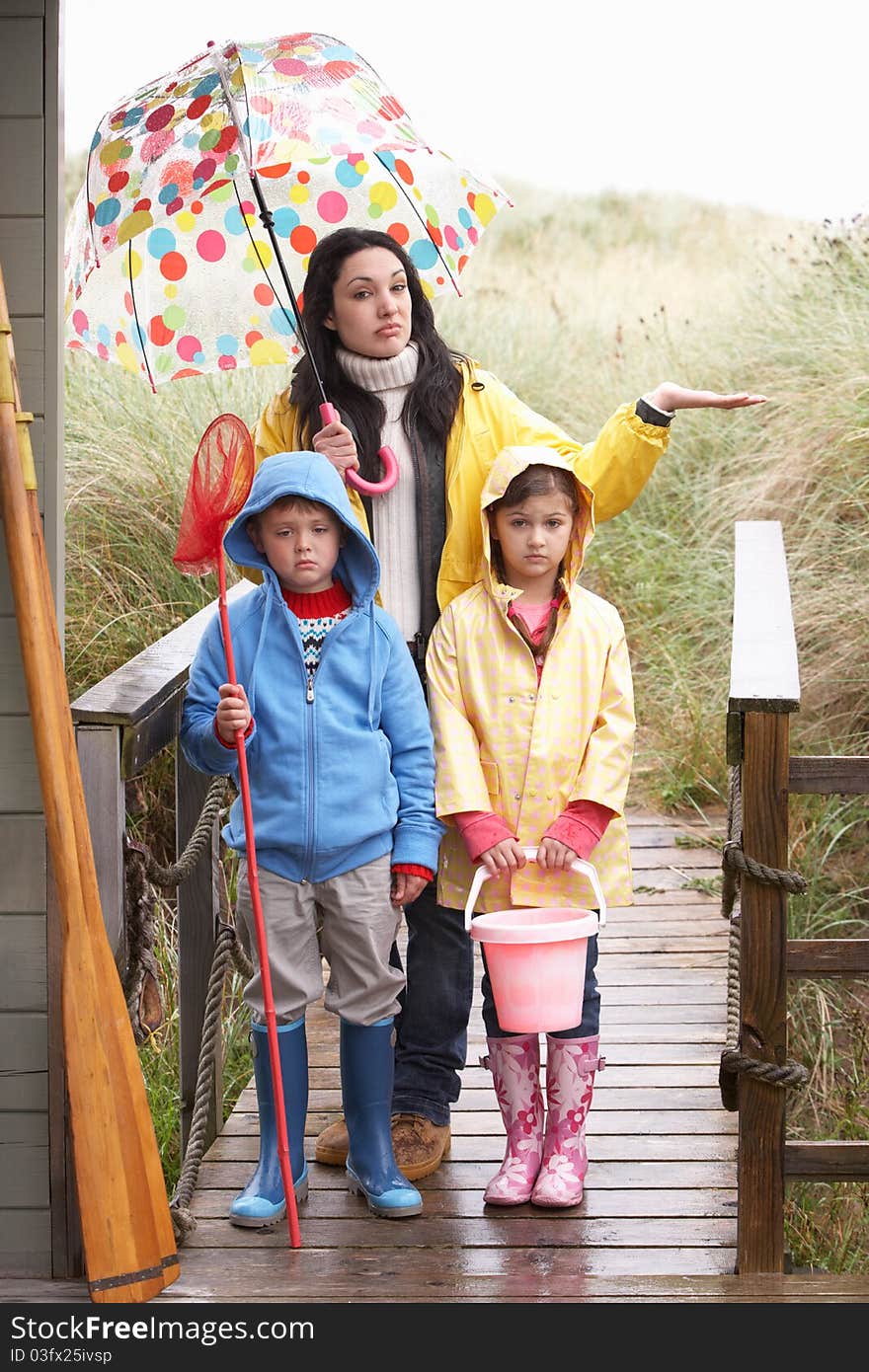 Sad mother and children on beach looking at camera