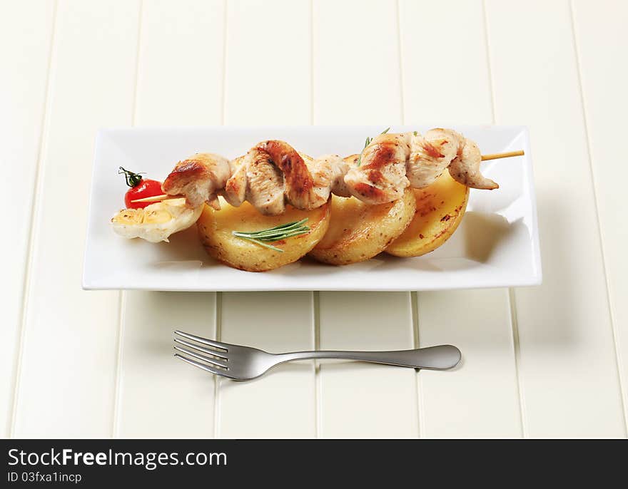 Chicken skewer on roasted potatoes - closeup. Chicken skewer on roasted potatoes - closeup