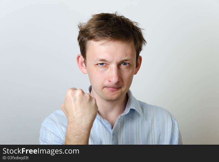 Dishevelled man in a blue shirt showing his fist. Dishevelled man in a blue shirt showing his fist.