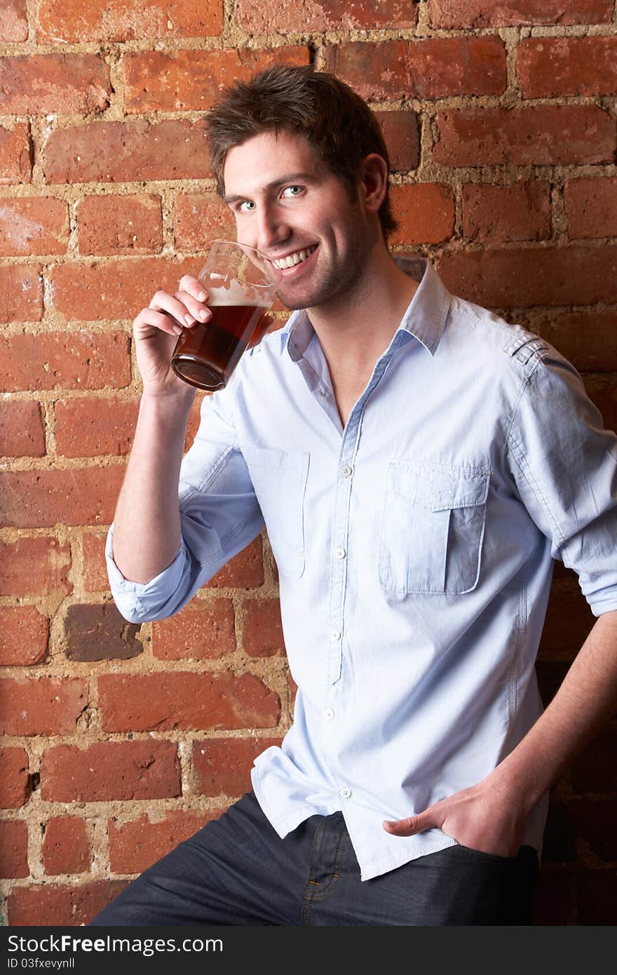 Portrait of young man drinking a pint smiling at camera