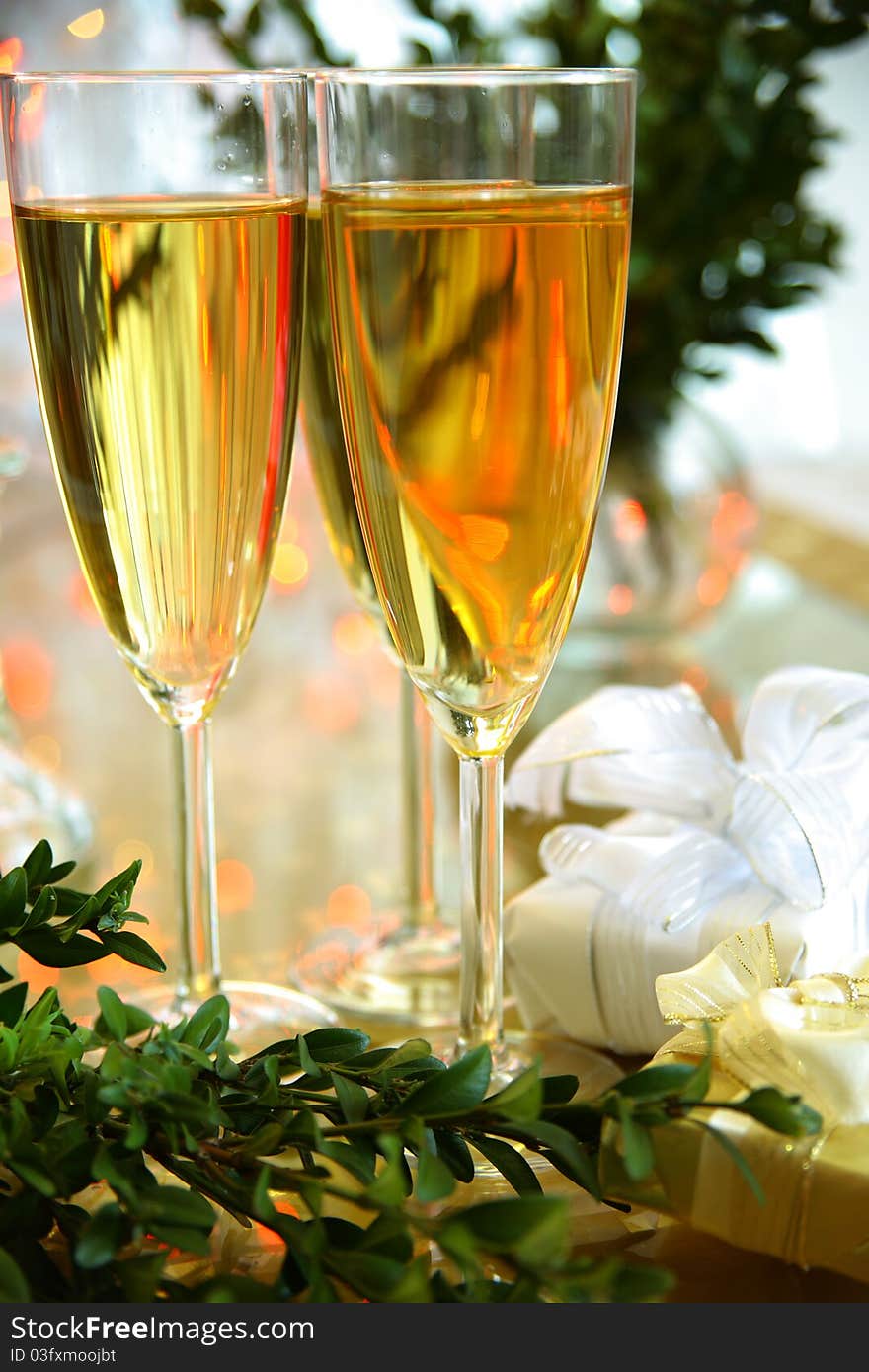 Close-up of champagne in glasses ,green twig and blured lights on background. Close-up of champagne in glasses ,green twig and blured lights on background