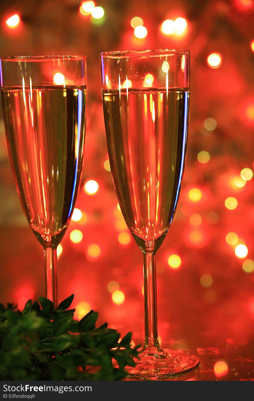 Close-up of champagne in glasses, green twig and blured lights on background. Close-up of champagne in glasses, green twig and blured lights on background