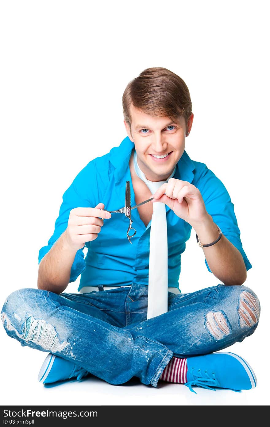 The young beautiful man hairdresser wearing blue shirt and white tie holding two scissors sitting on the isolated white background. The young beautiful man hairdresser wearing blue shirt and white tie holding two scissors sitting on the isolated white background