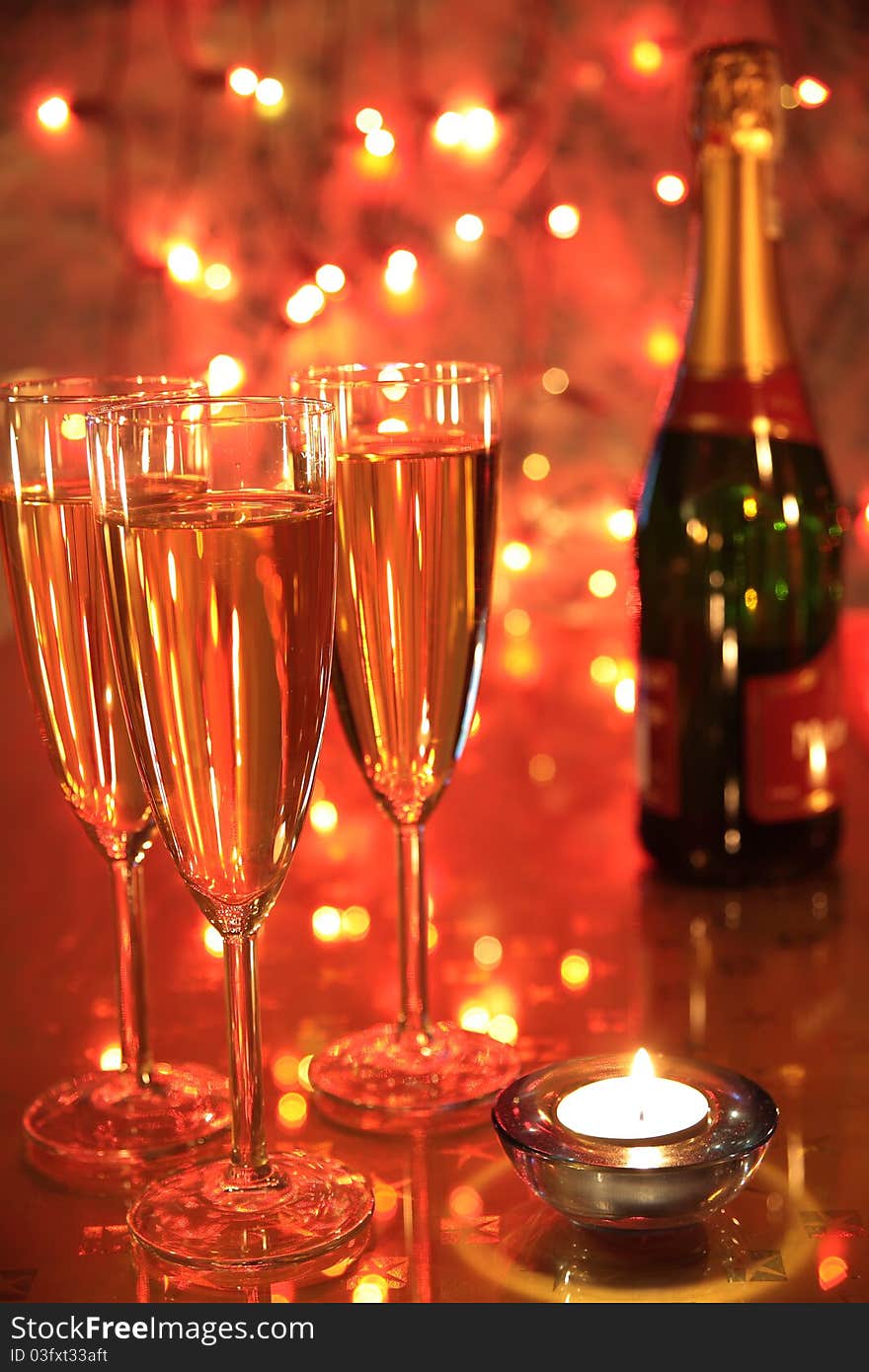 Champagne in glasses, cadlelight and blured lights on red background. Champagne in glasses, cadlelight and blured lights on red background.