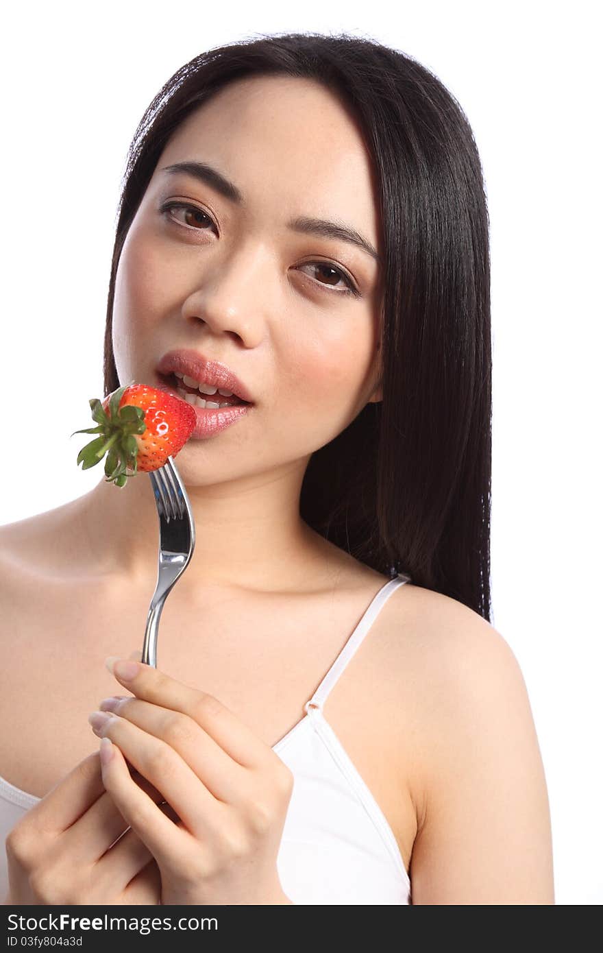 Close up of beautiful sexy young chinese girl, with long black hair, about to bite into a fresh strawberry fruit on a fork. Close up of beautiful sexy young chinese girl, with long black hair, about to bite into a fresh strawberry fruit on a fork.