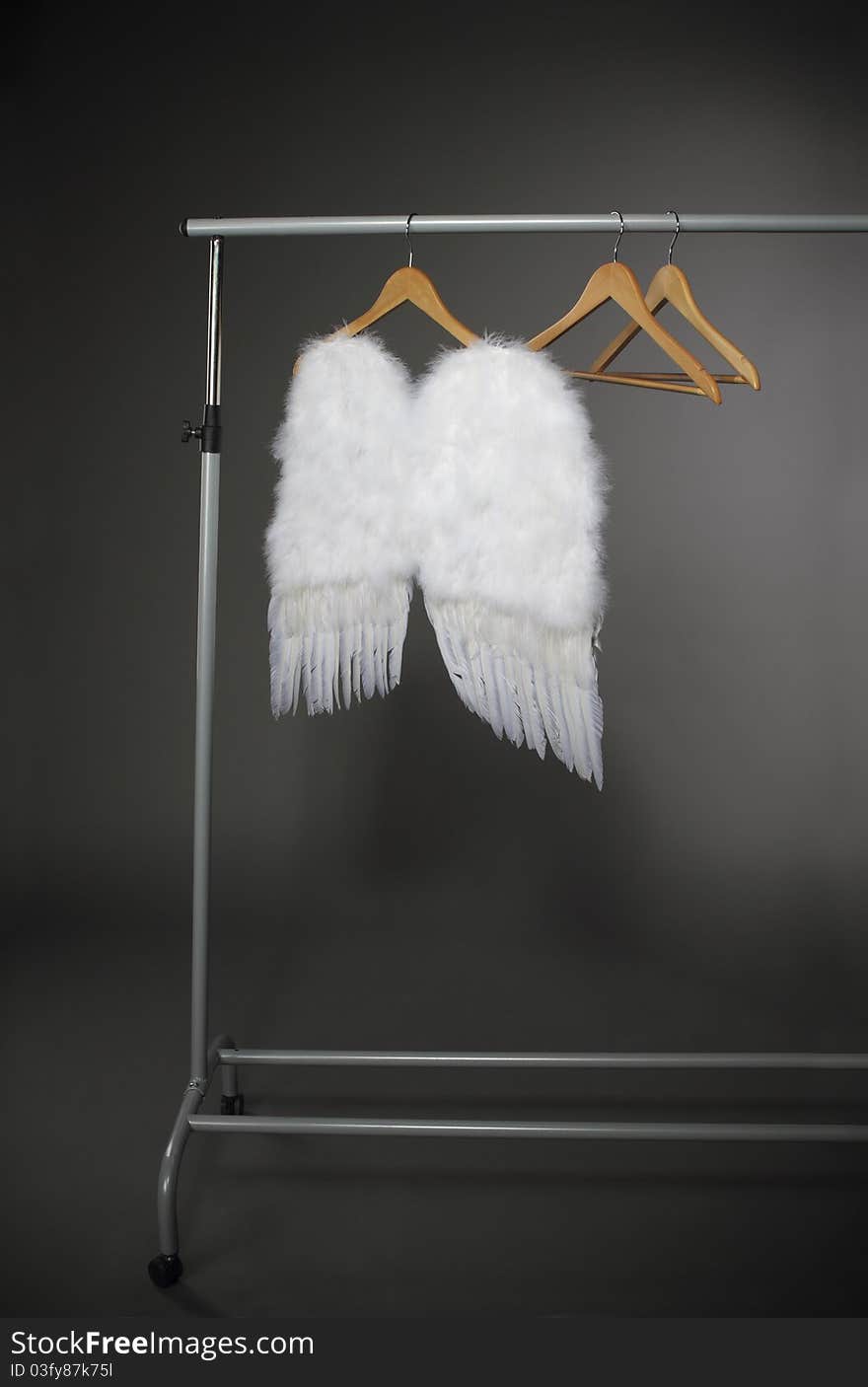 Wooden hangers and white wings on the grey background