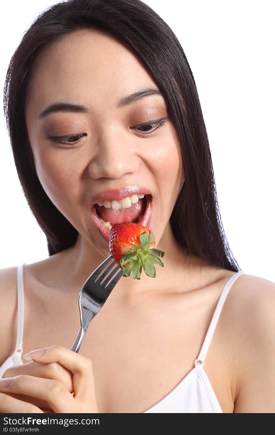 Chinese beautiful teenager girl with long black hair, mouth wide open, eating a fresh strawberry fruit on a fork. Chinese beautiful teenager girl with long black hair, mouth wide open, eating a fresh strawberry fruit on a fork.