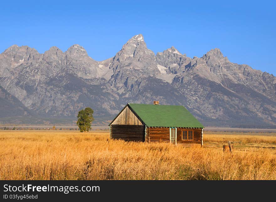 Abandoned house in prairie landscape with Grand Tetons background