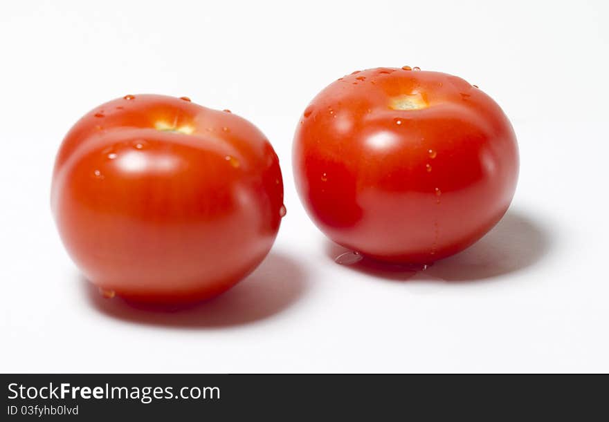 Two red tomatos wet on white background