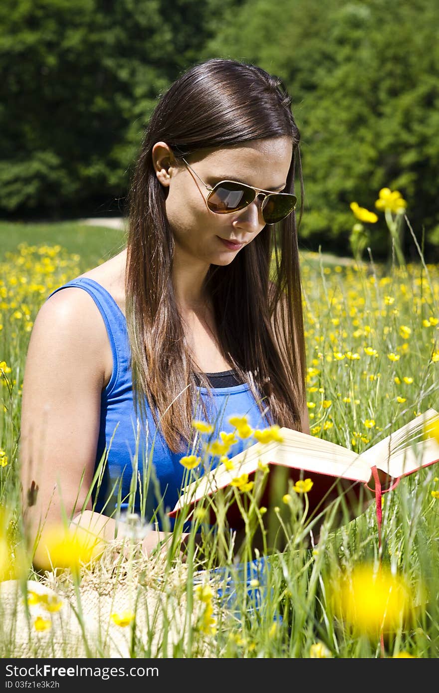 Beautiful young girl in the park reading a book