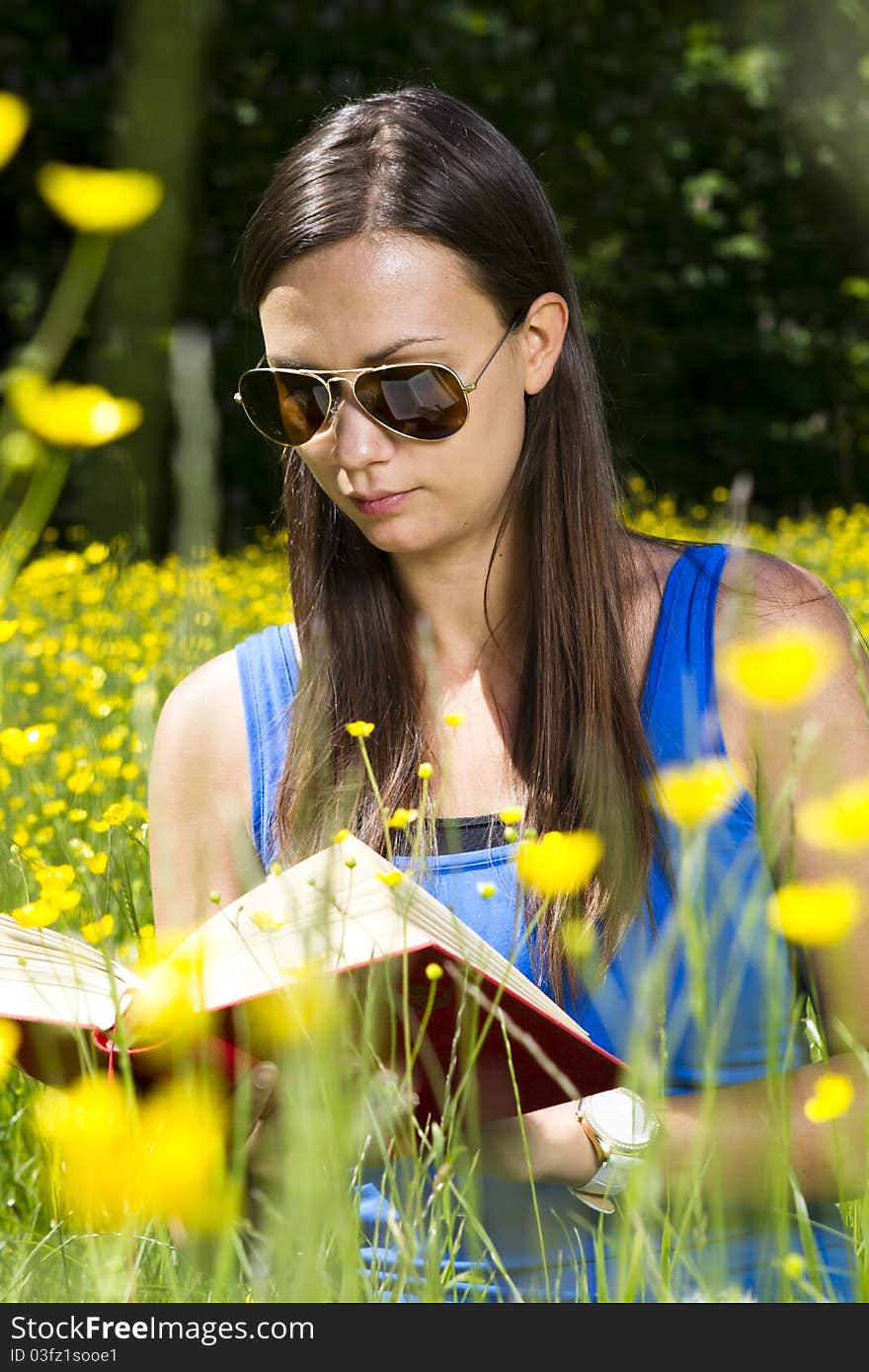 Beautiful young girl in the park reading a book