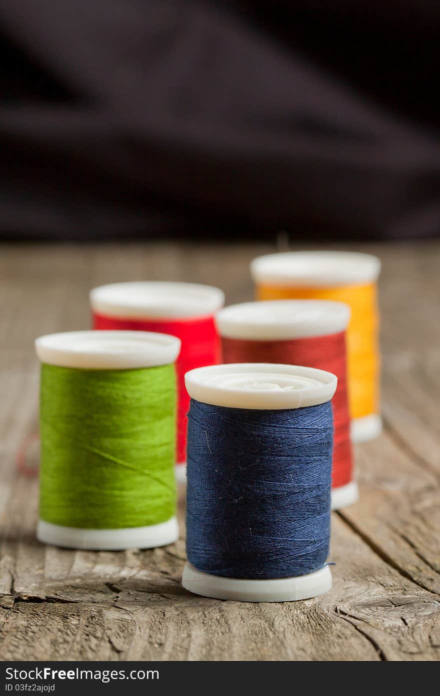 Spools of colorful threads on old wooden table