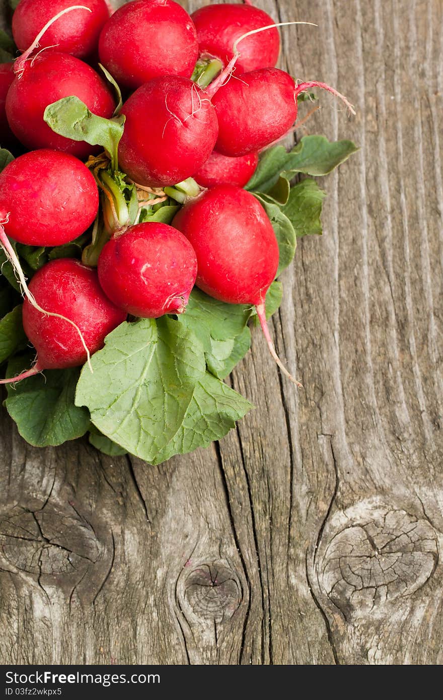 Top view on bunch of fresh radishes on old wooden table