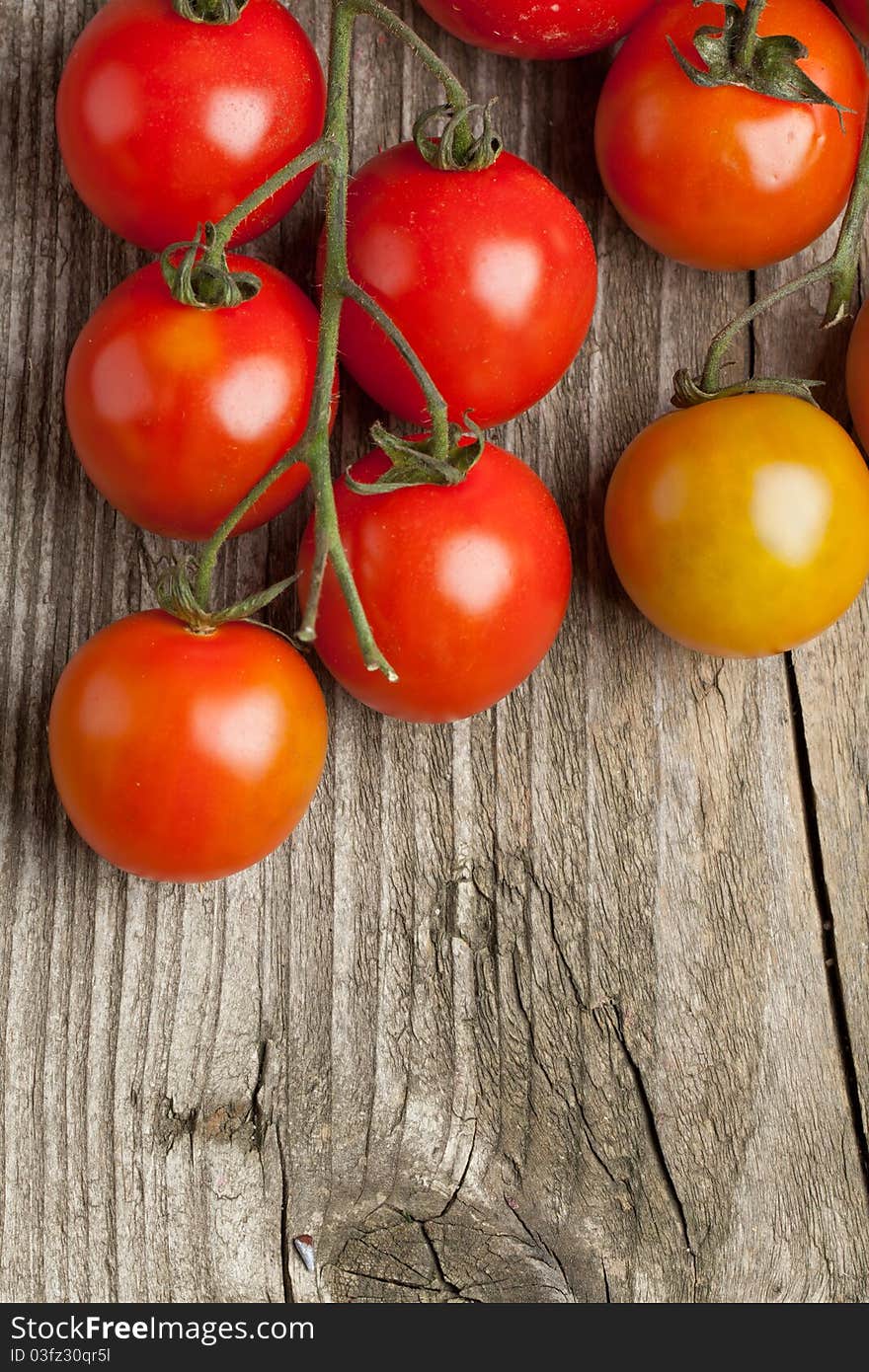 Top view on branch of fresh cherry tomatoes on old wooden background