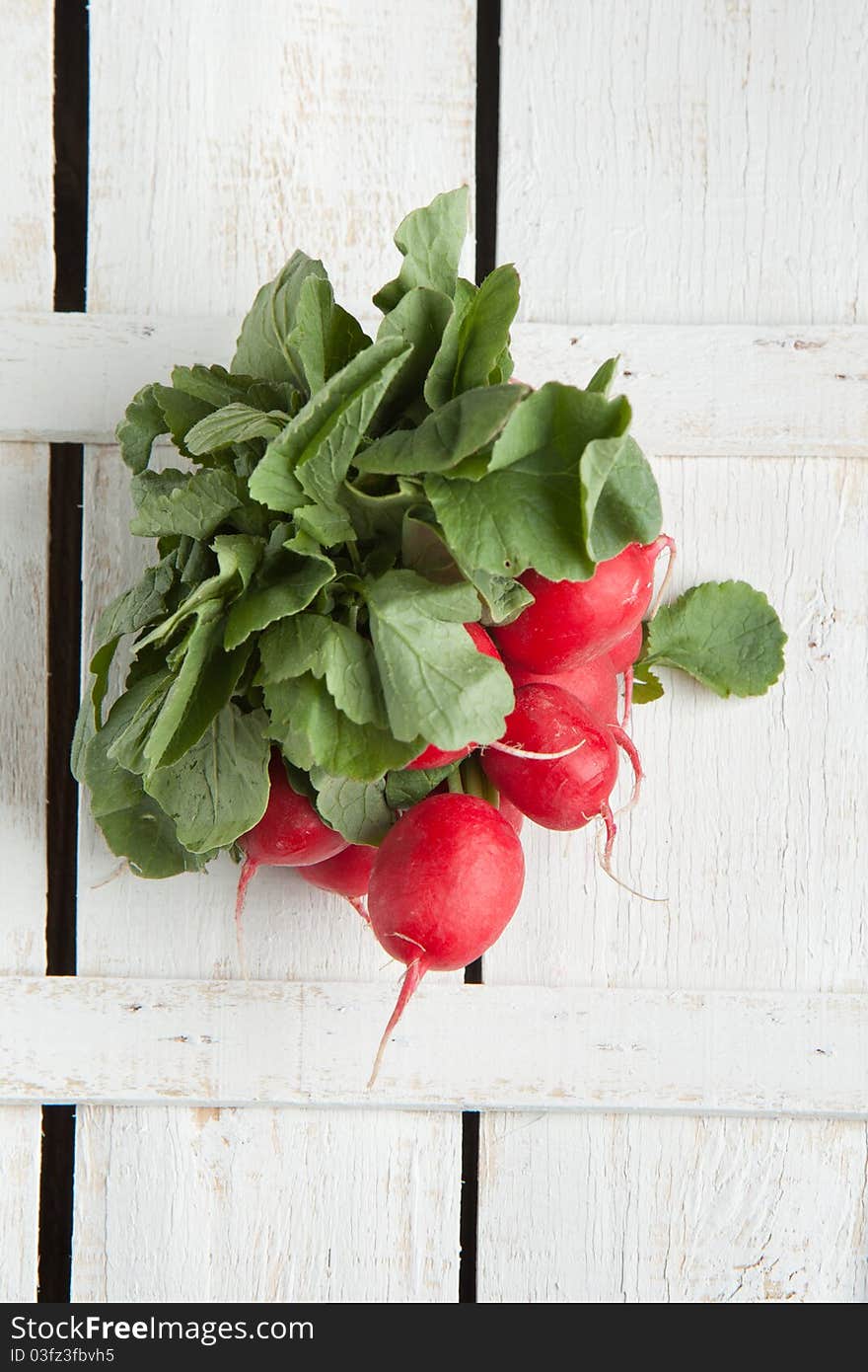 Top view on bunch of fresh radishes on white wooden table