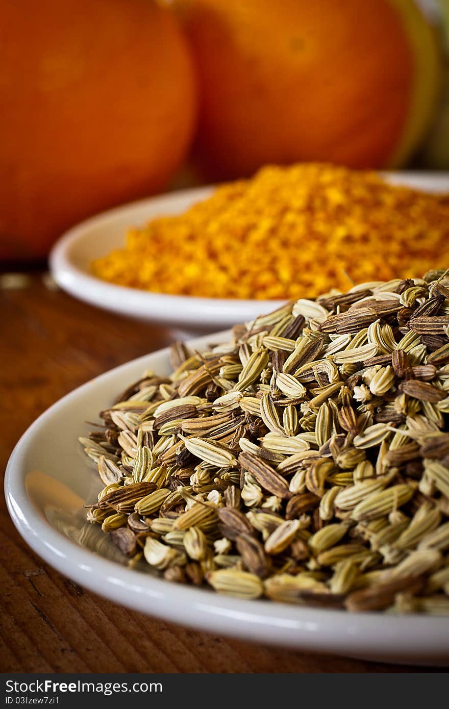 High contrast cuisine: fennel seeds and dry orange rind. Focus on fennel seeds in the foreground. High contrast cuisine: fennel seeds and dry orange rind. Focus on fennel seeds in the foreground.