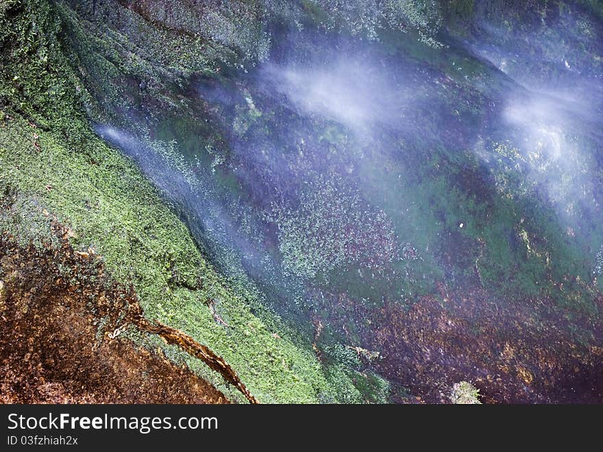 Detail of a beautiful and colored grotto wall with the water falling on it