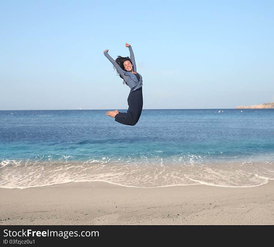 Smiling woman jumping on a beach. Smiling woman jumping on a beach