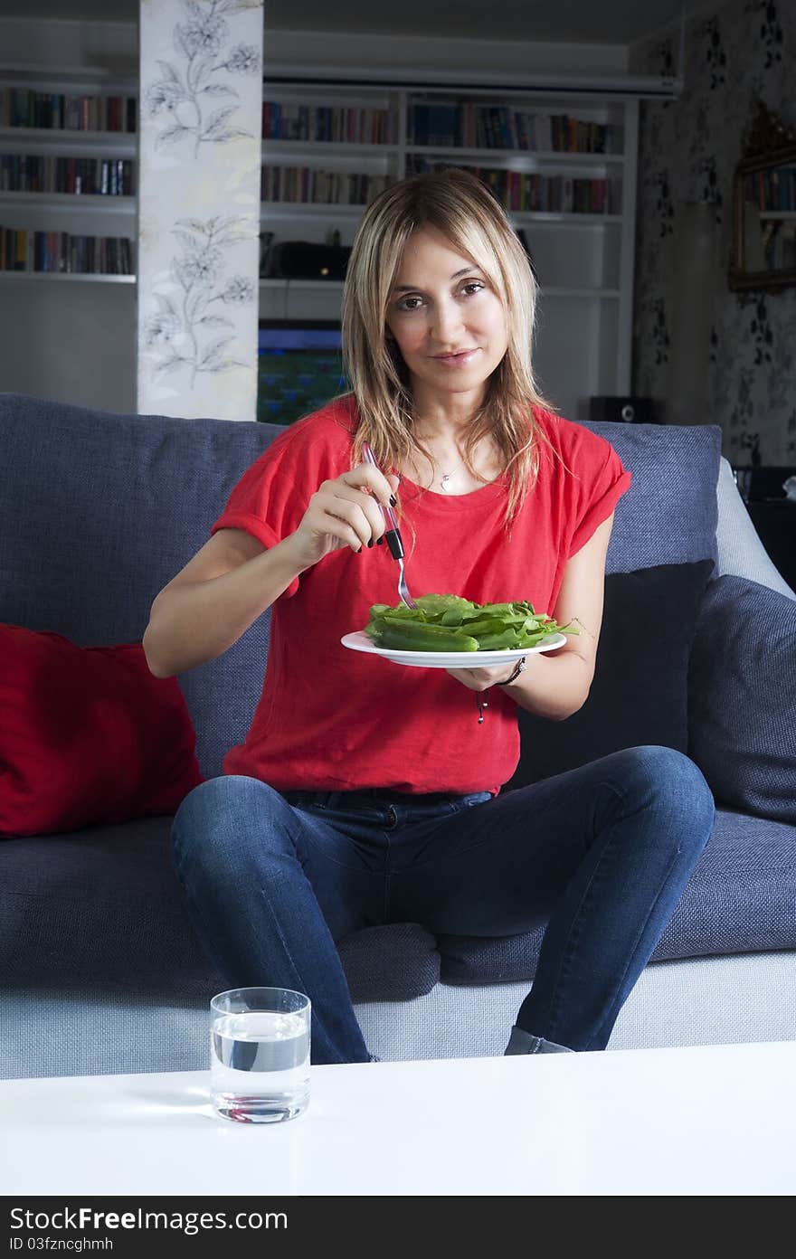 Beautiful blond woman eating green leaves as a healthy meal