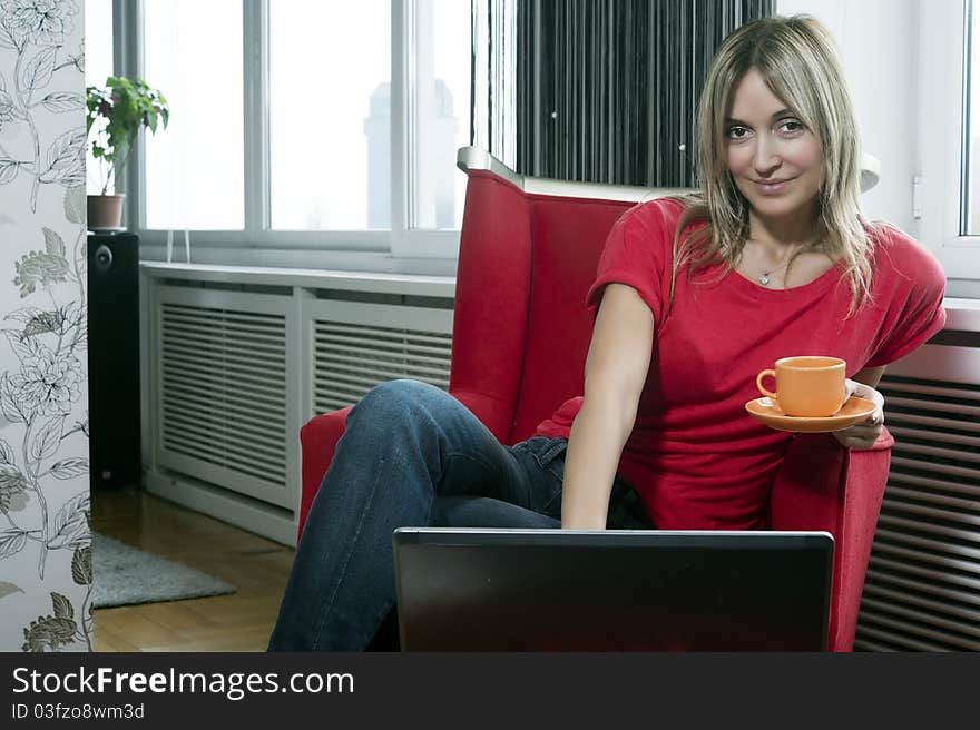 Beautiful blond woman having her morning coffee and working on her laptop