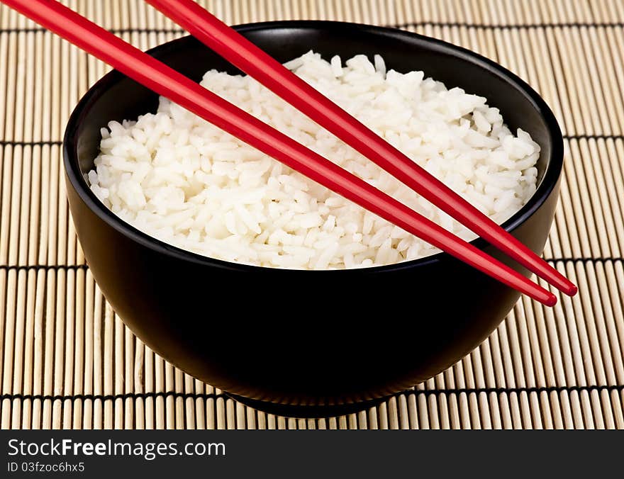 A bowl of rice with chop sticks representing an Asian staple. A bowl of rice with chop sticks representing an Asian staple