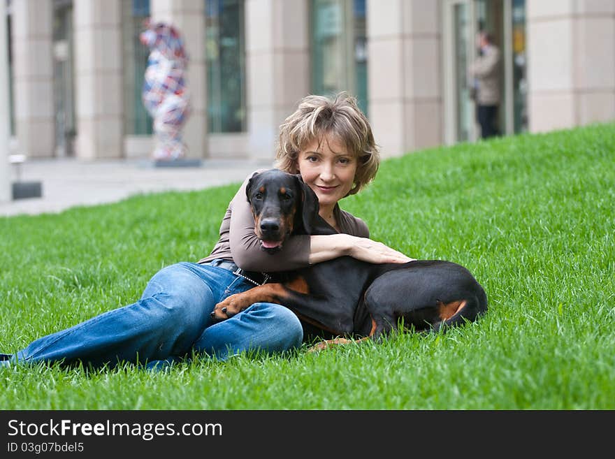 The young woman with a doberman dog on a grass. The young woman with a doberman dog on a grass