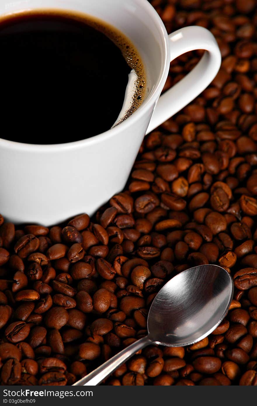 Cup of coffee with spoon on roasted coffee beans. Cup of coffee with spoon on roasted coffee beans