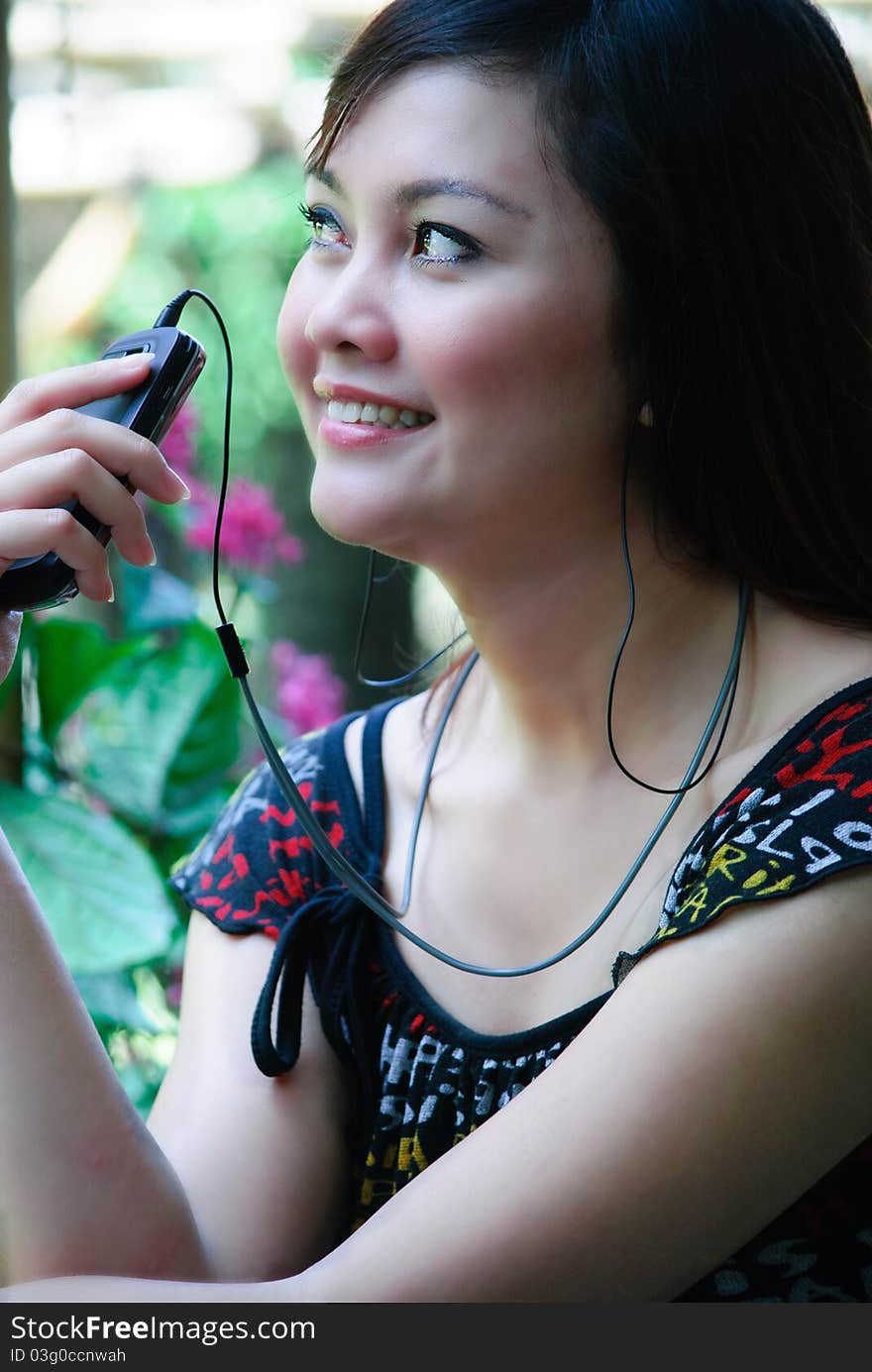 A girl is listening music from her handphone. A girl is listening music from her handphone