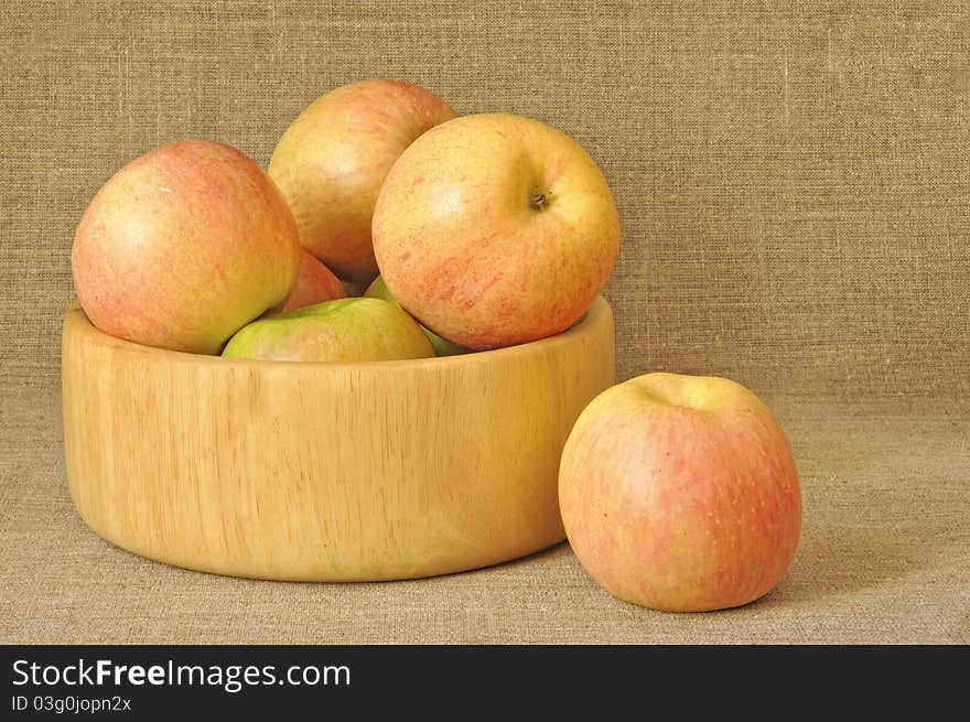 Apples in a wooden plate against from a sacking