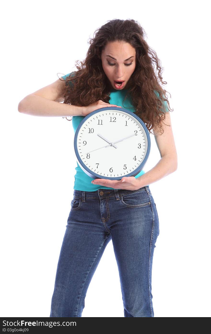 Surprised at the time, a beautiful young woman holding a large clock. She has long brown hair and is wearing blue jeans and turqoise t-shirt. Surprised at the time, a beautiful young woman holding a large clock. She has long brown hair and is wearing blue jeans and turqoise t-shirt.