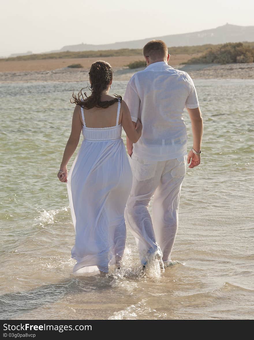 Young newly married couple walking together on a tropical beach. Young newly married couple walking together on a tropical beach