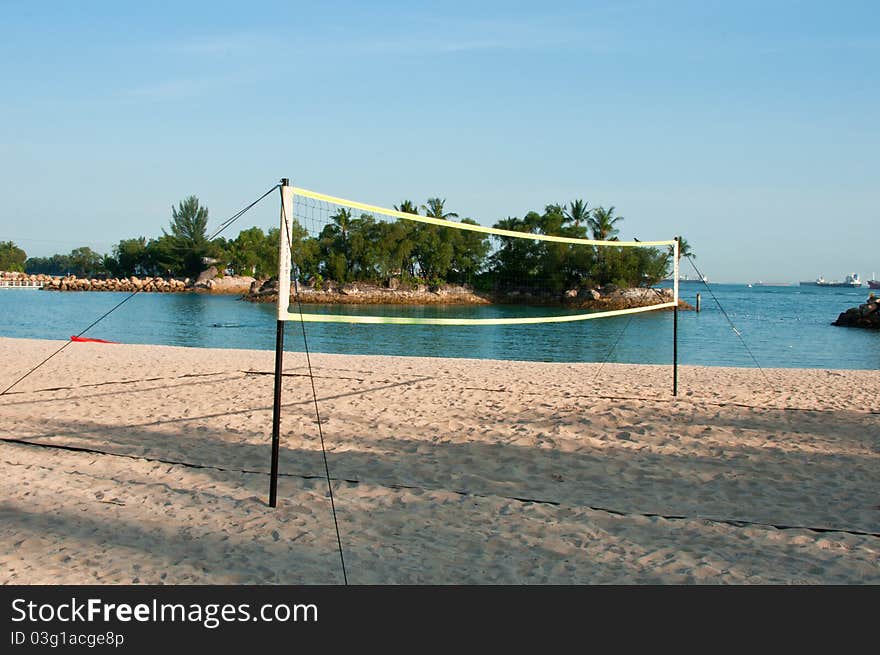 Beach volley ball net with palm tree island at the background