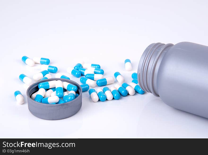 Plastic container with medicine in blue and white capsules. Plastic container with medicine in blue and white capsules