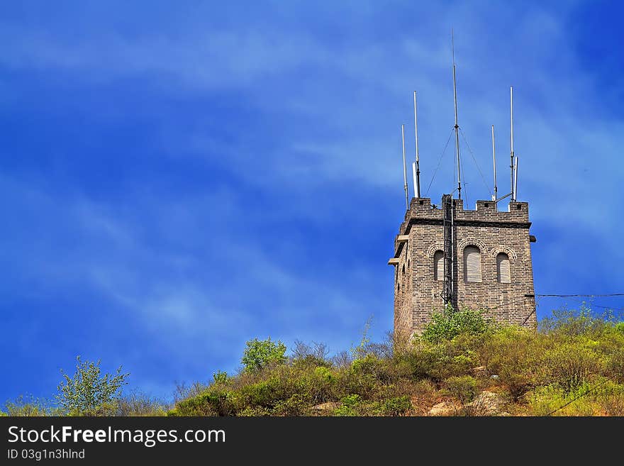 A communication tower stands on a moutain under blue sky. A communication tower stands on a moutain under blue sky