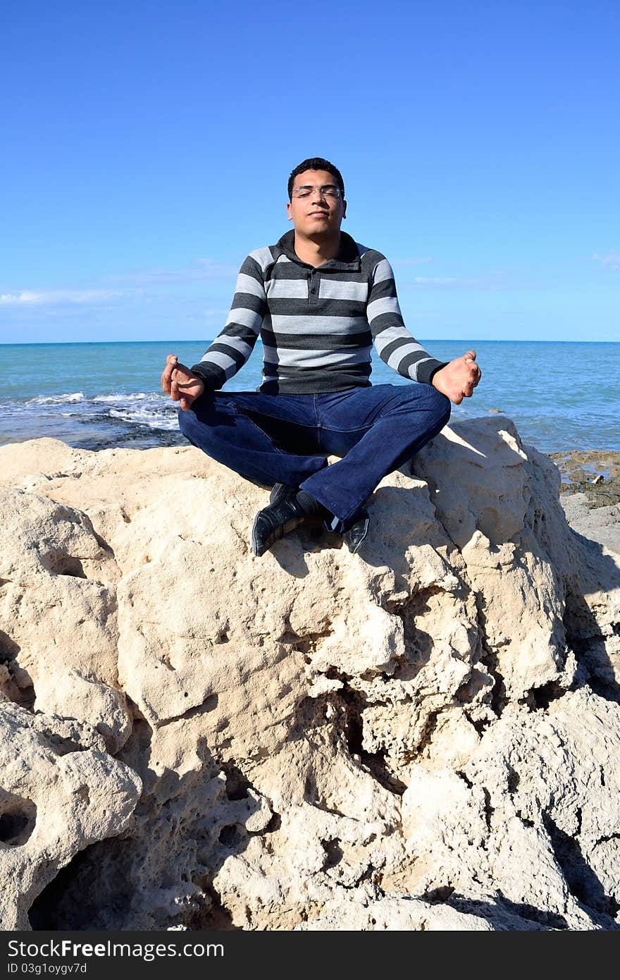 Arab man meditating sitting on rocks at the coast of tunisia. Arab man meditating sitting on rocks at the coast of tunisia.