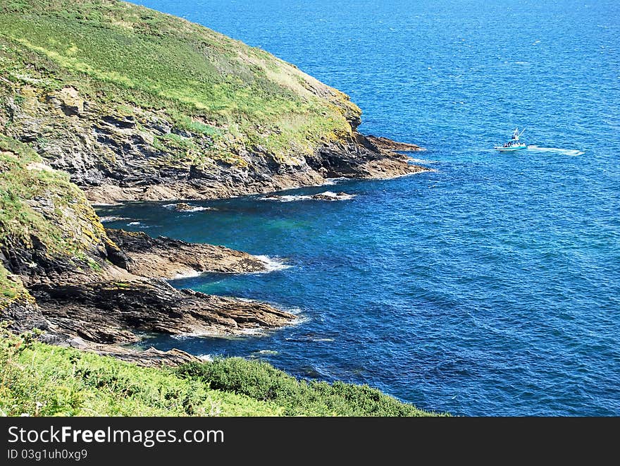 Blue Sea and a Fishingboat taken from the cliffs of a headland in Cornwall in Summer. Blue Sea and a Fishingboat taken from the cliffs of a headland in Cornwall in Summer