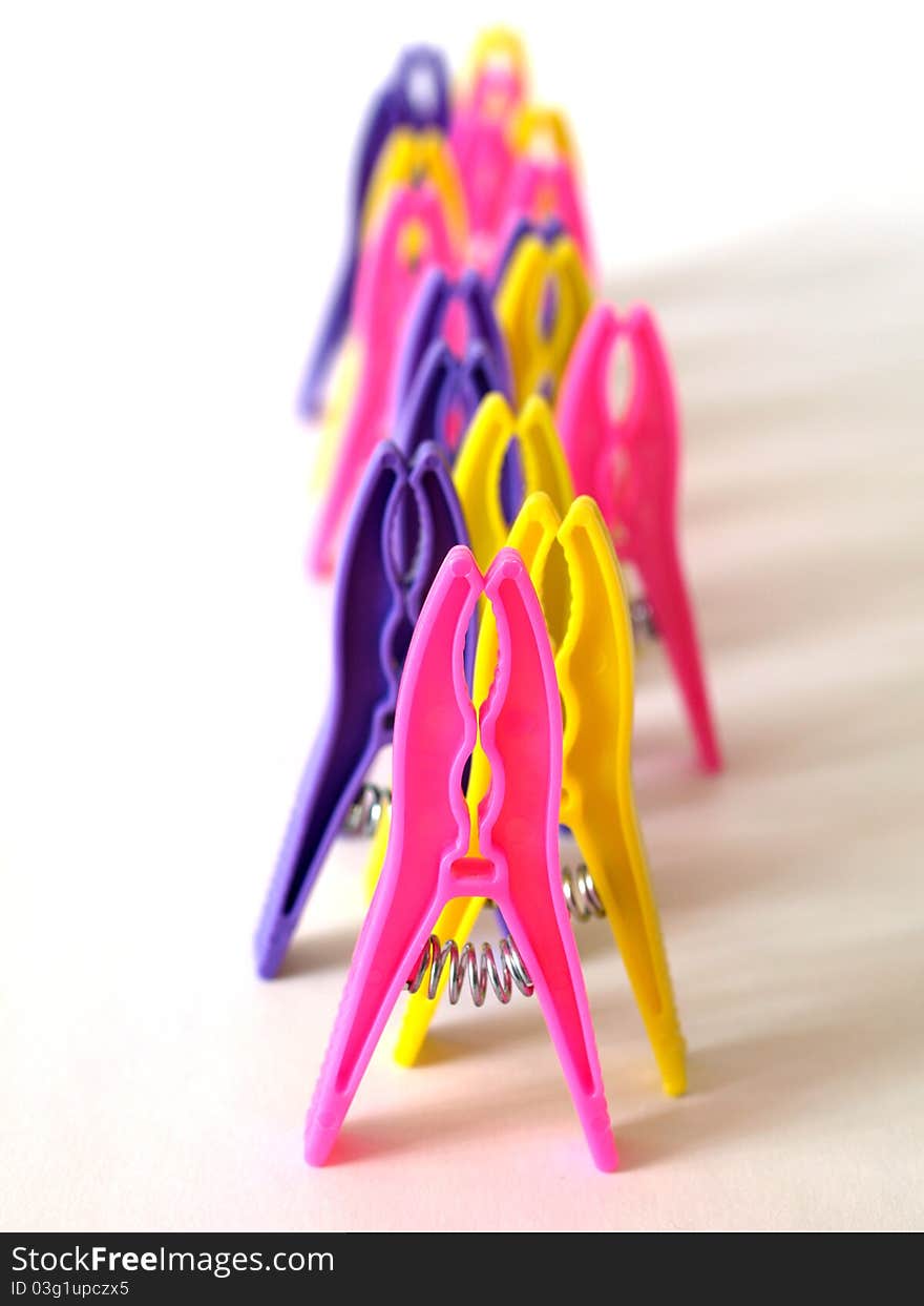 Bright clothes pegs standing in line one by one