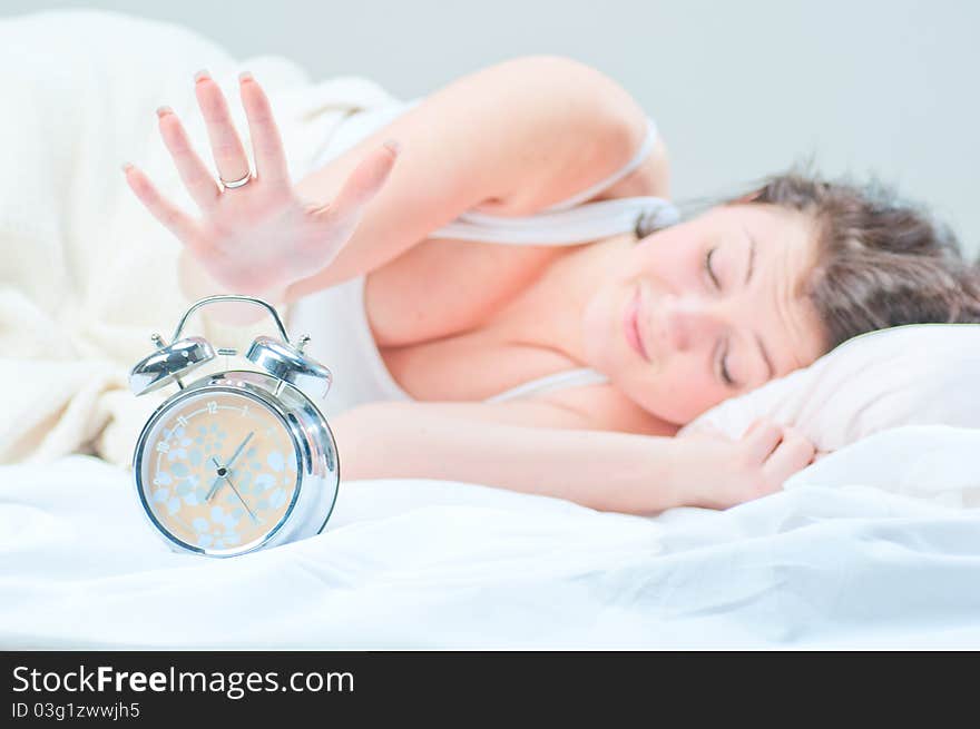 The girl tries to ungear an alarm clock at bedroom