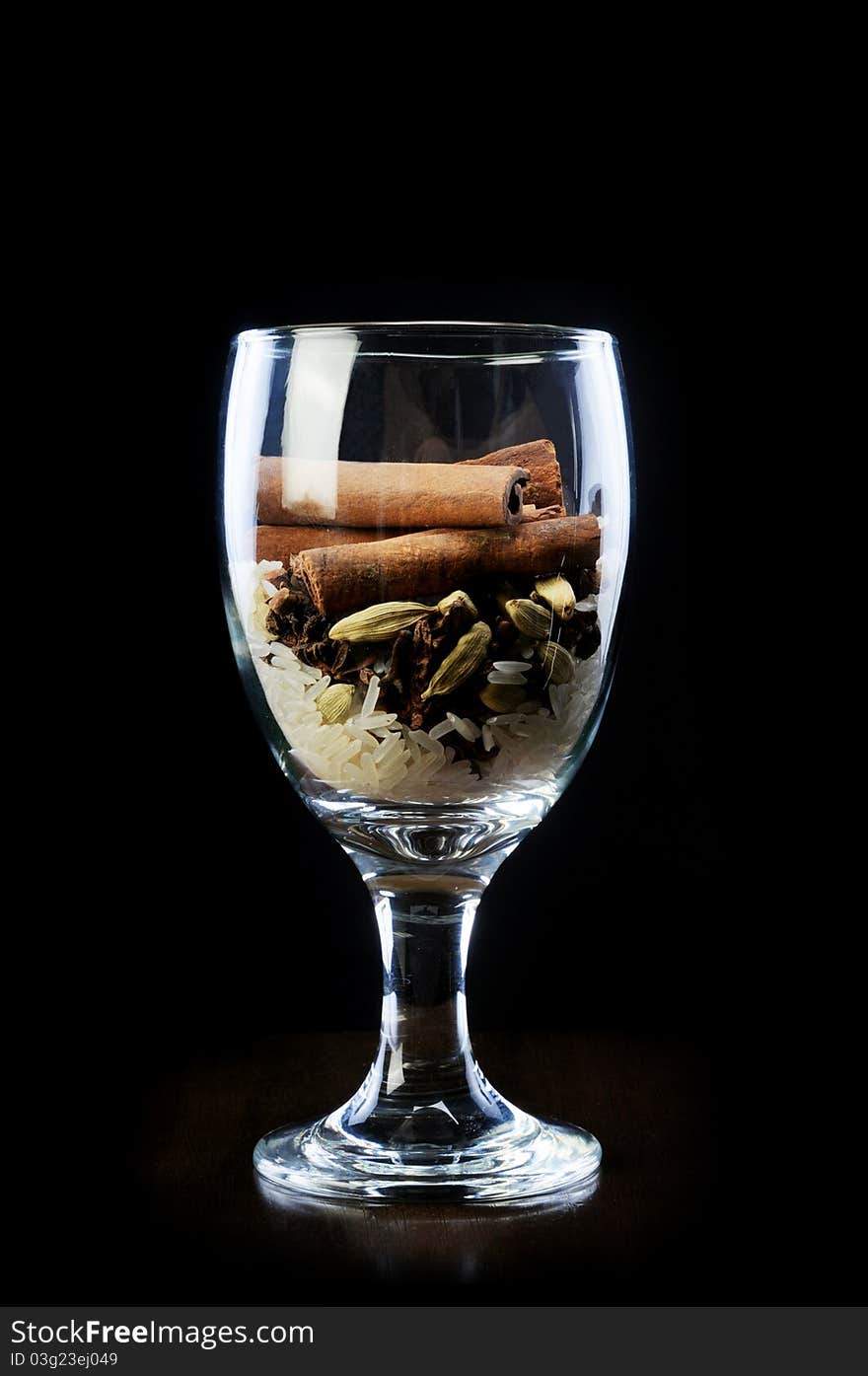 Star anise and rice with cinnamon sticks in wine glass isolaed black background