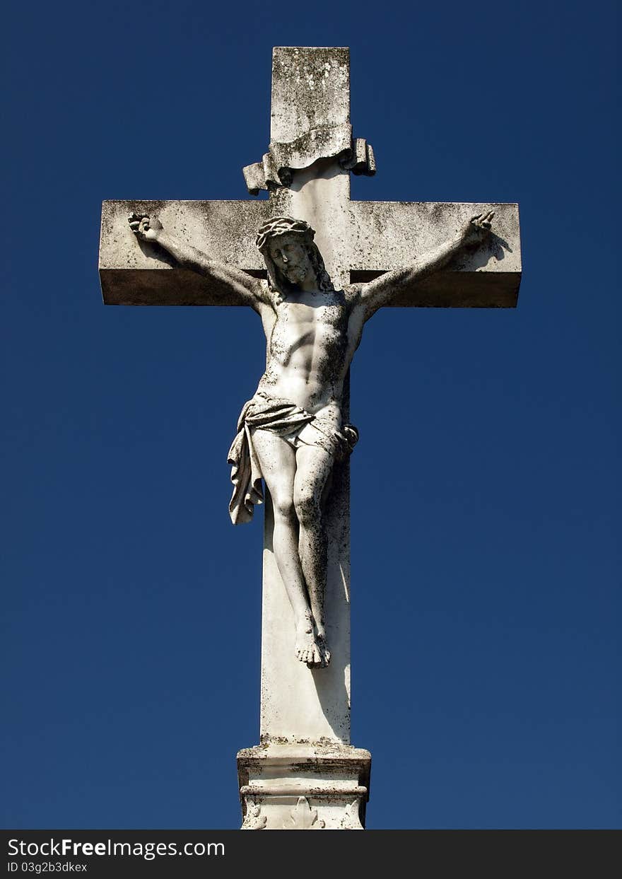 Old stone cross whit Christ over blue sky