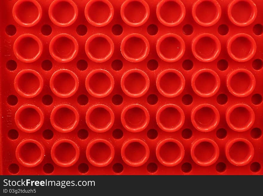 Closeup of a toy part showing circles on red plastic.