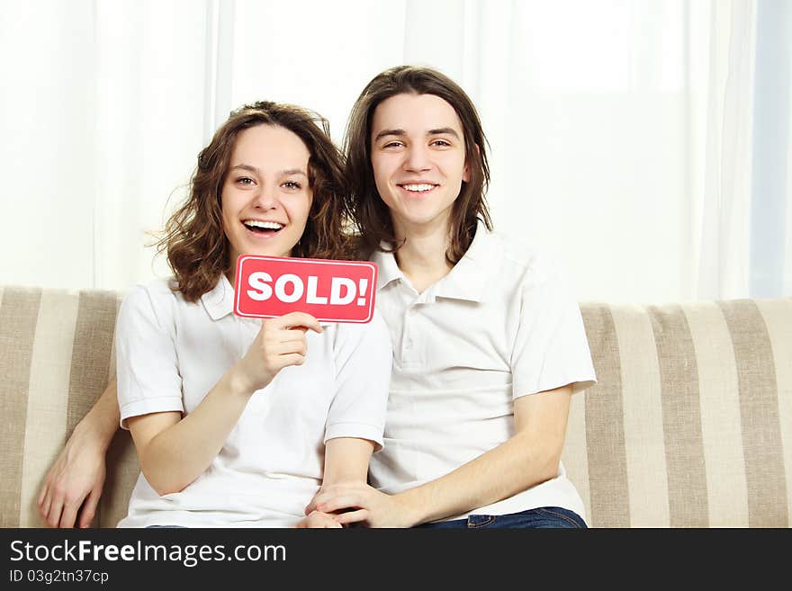 Closeup of a couple sitting at home on the couch laughing, hugging and holding a plate sold. Closeup of a couple sitting at home on the couch laughing, hugging and holding a plate sold