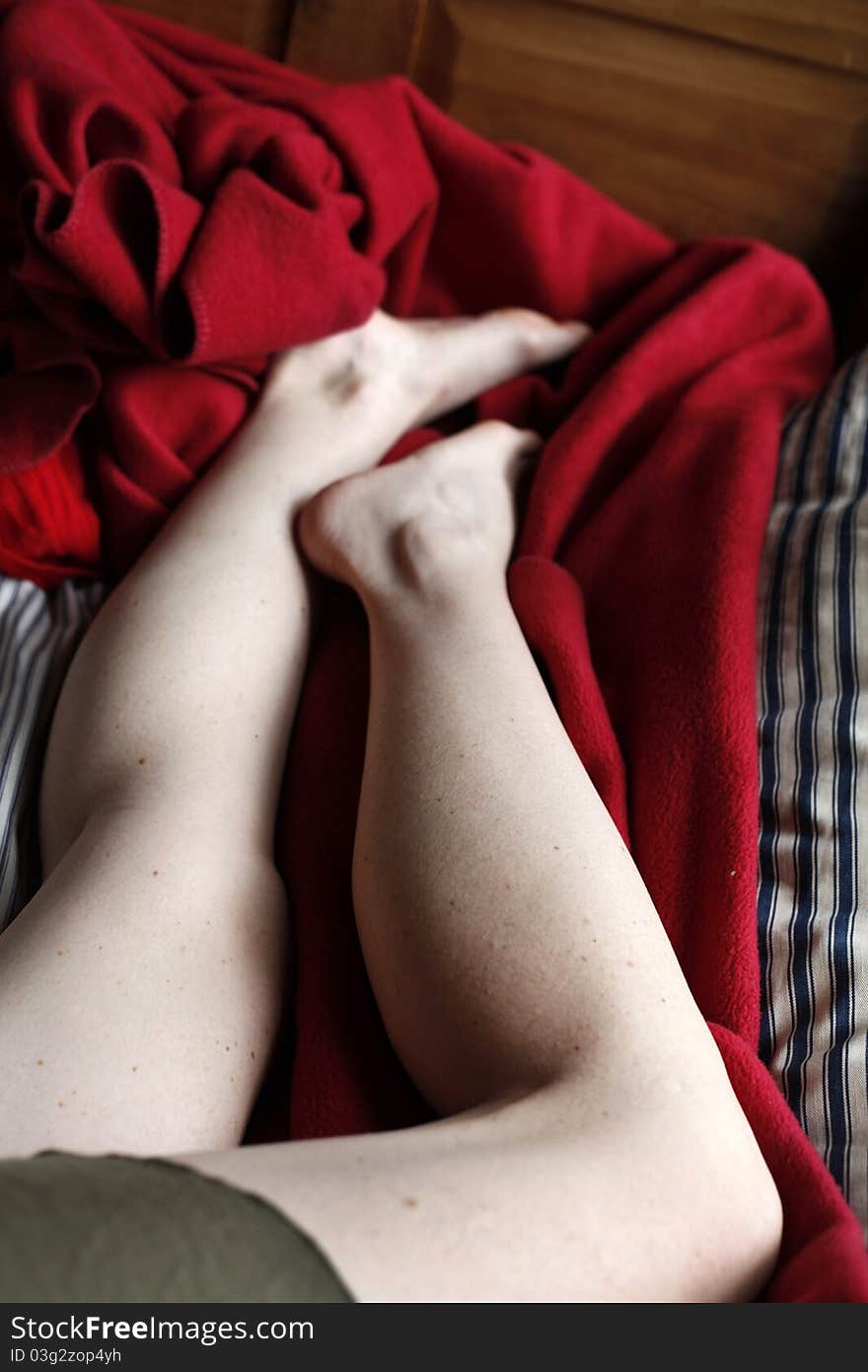 A woman's legs on a red blanket while taking a nap. A woman's legs on a red blanket while taking a nap.