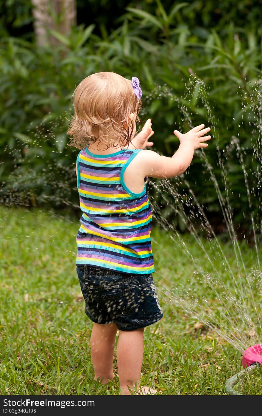 Little girl playing with a garden hose. Little girl playing with a garden hose