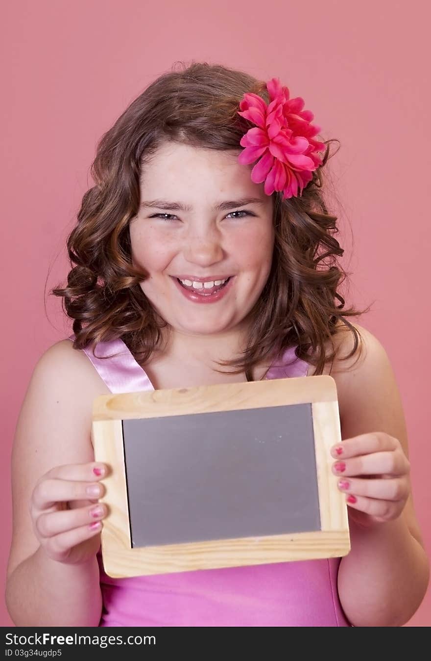 Smiling young preteen holding a mini chalkboard for school. Smiling young preteen holding a mini chalkboard for school